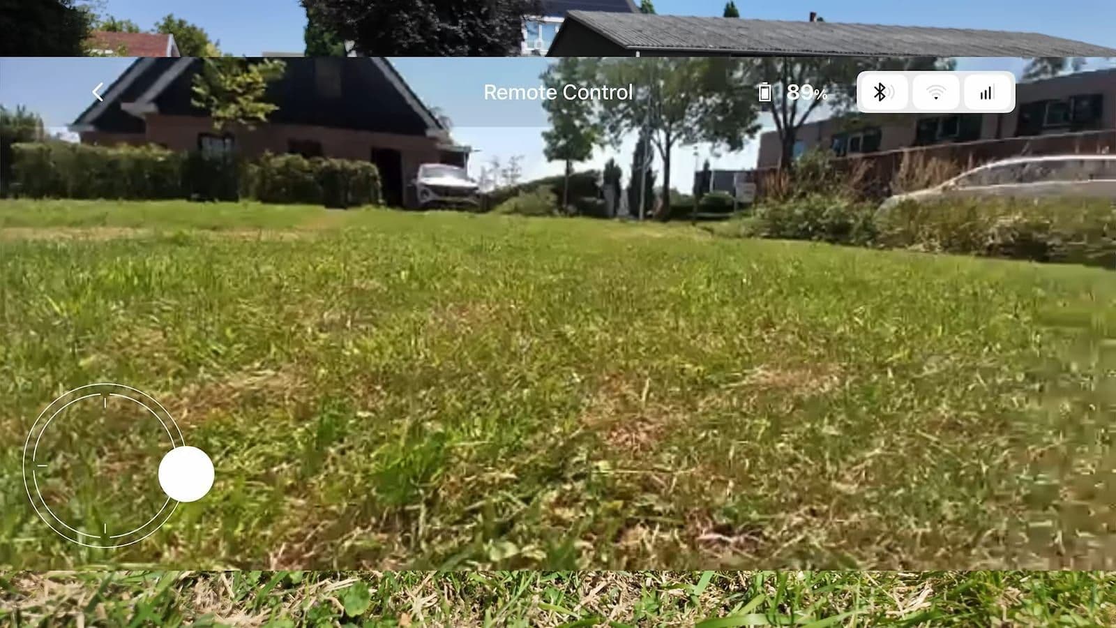 Het beeldscherm van de smartphone toont het camerabeeld op grasniveau met een virtuele joystick