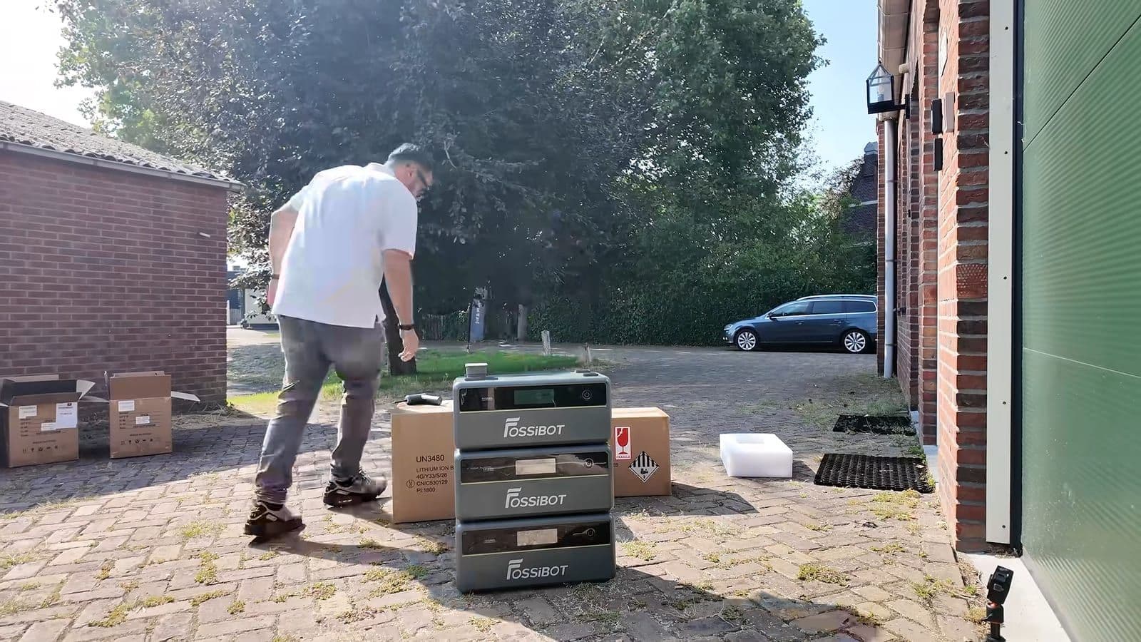 Zino loopt langs een half opgebouwde Fossibot-stapel met lege dozen op de oprit