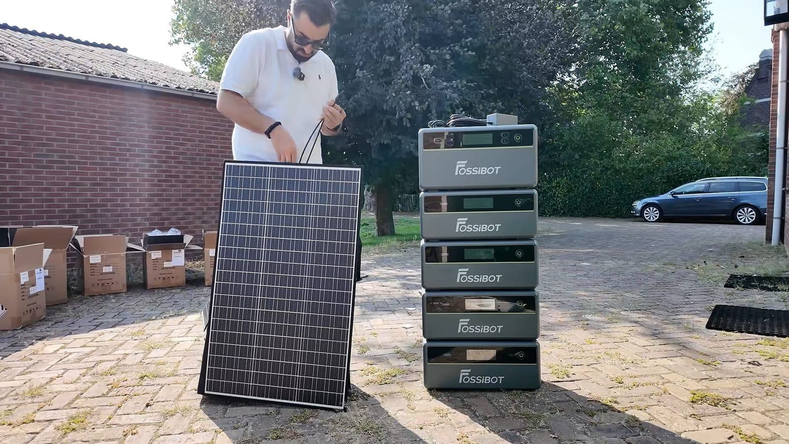 Zino sluit de kabels van een zonnepaneel aan naast de gestapelde Fossibot-toren