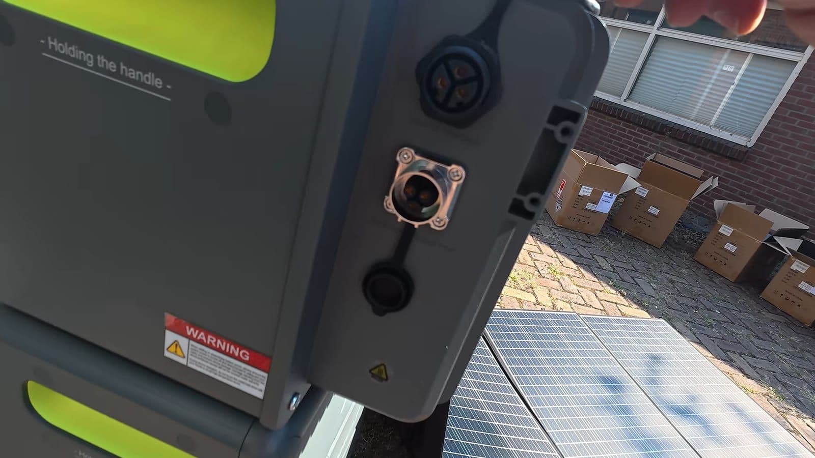Close-up van de zijkant van de basisunit met ronde aansluitingen en een waarschuwingssticker