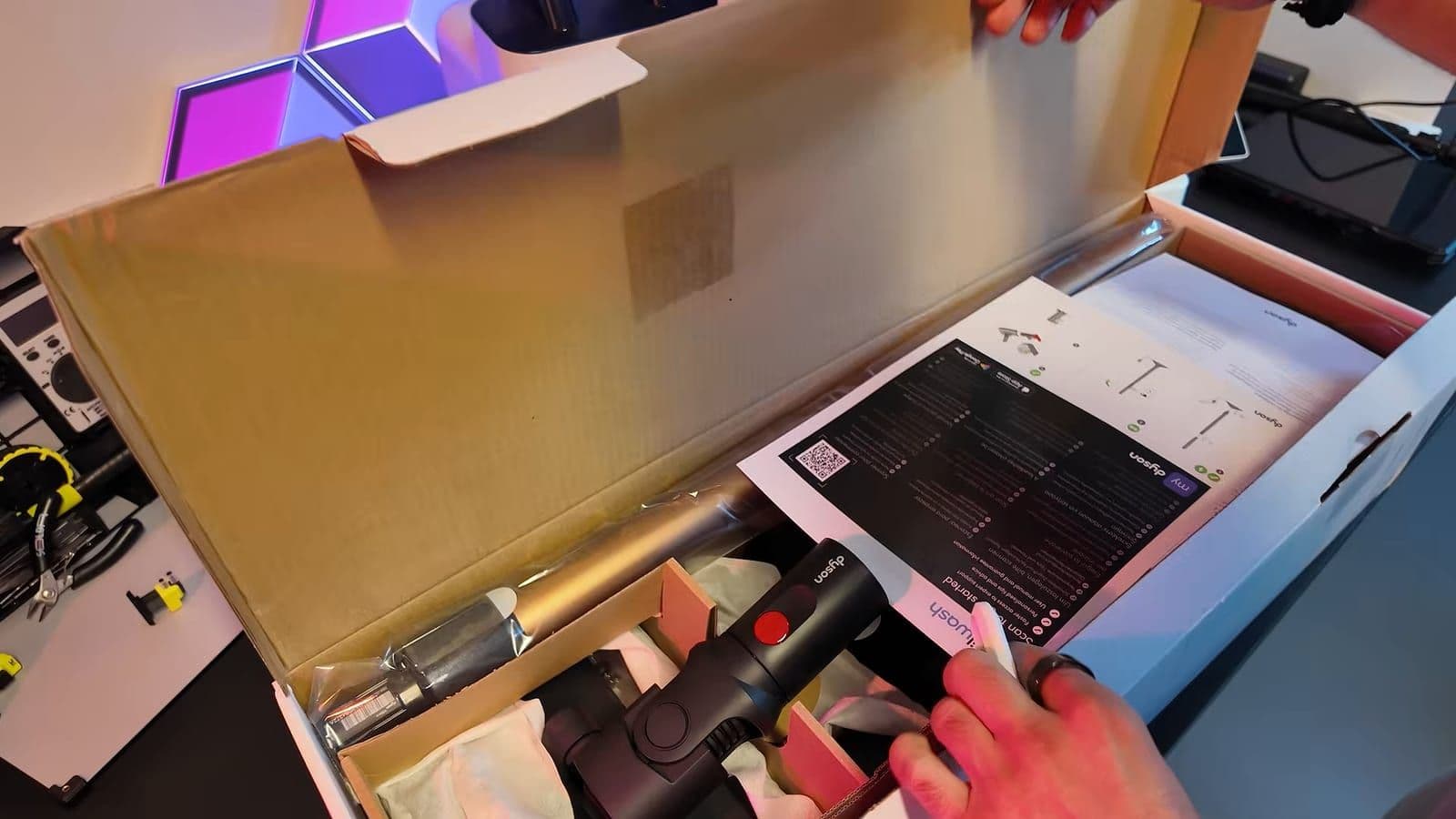 Geopende doos van de Dyson PencilWash met handleiding, steel en handgreep met rode knop