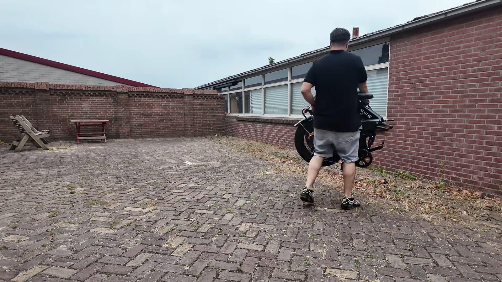 Zino tilt de ingeklapte fatbike op met twee handen op de binnenplaats
