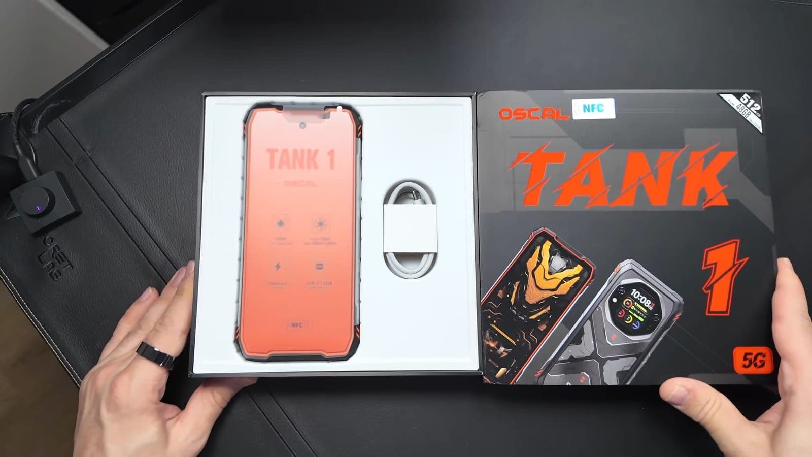 De geopende verpakking van de OSCAL Tank 1 met de oranje beschermfolie en de USB-C kabel zichtbaar