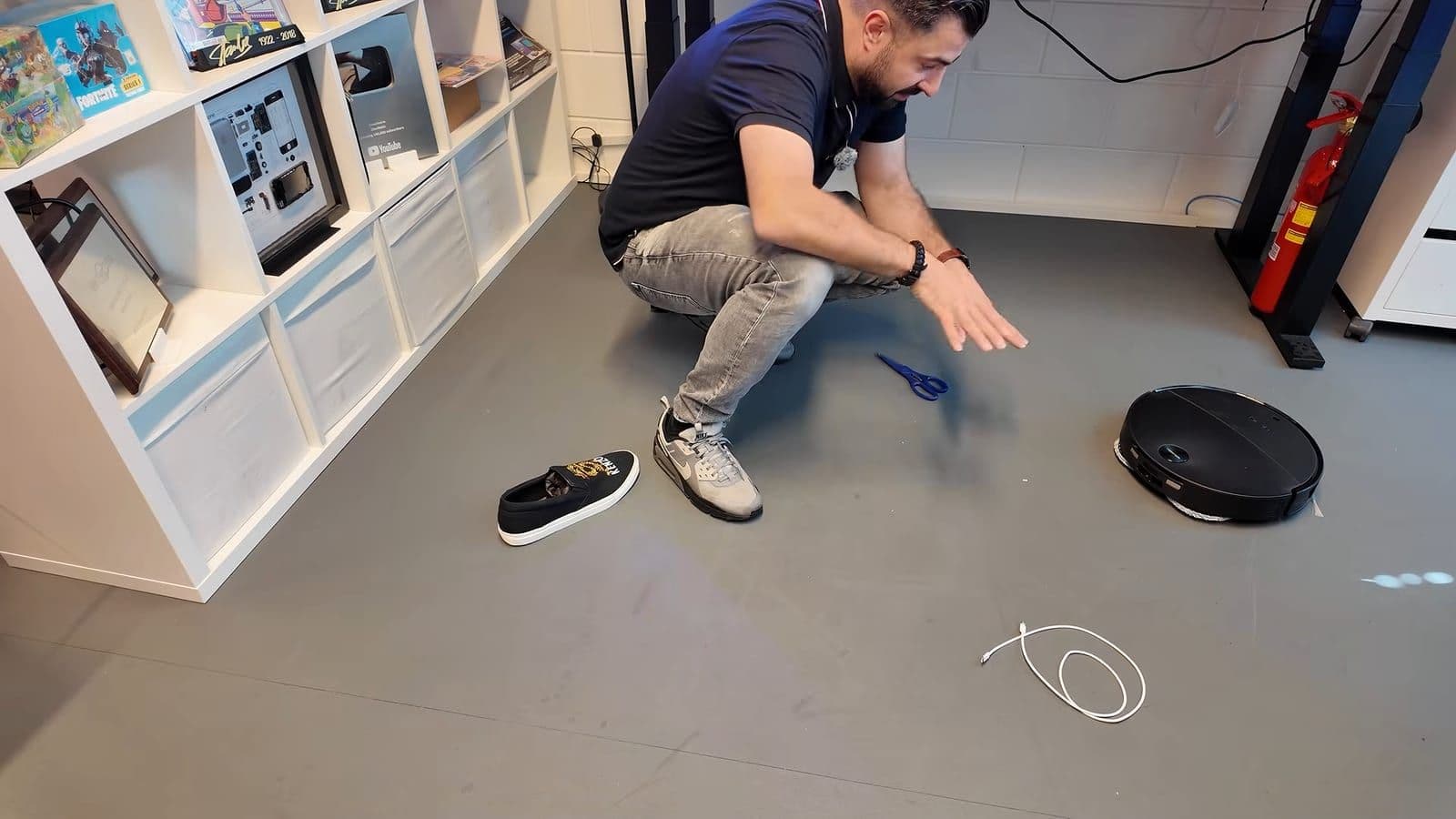Een schoen, een schaar en een witte oplaadkabel op de vloer voor de obstakeltest