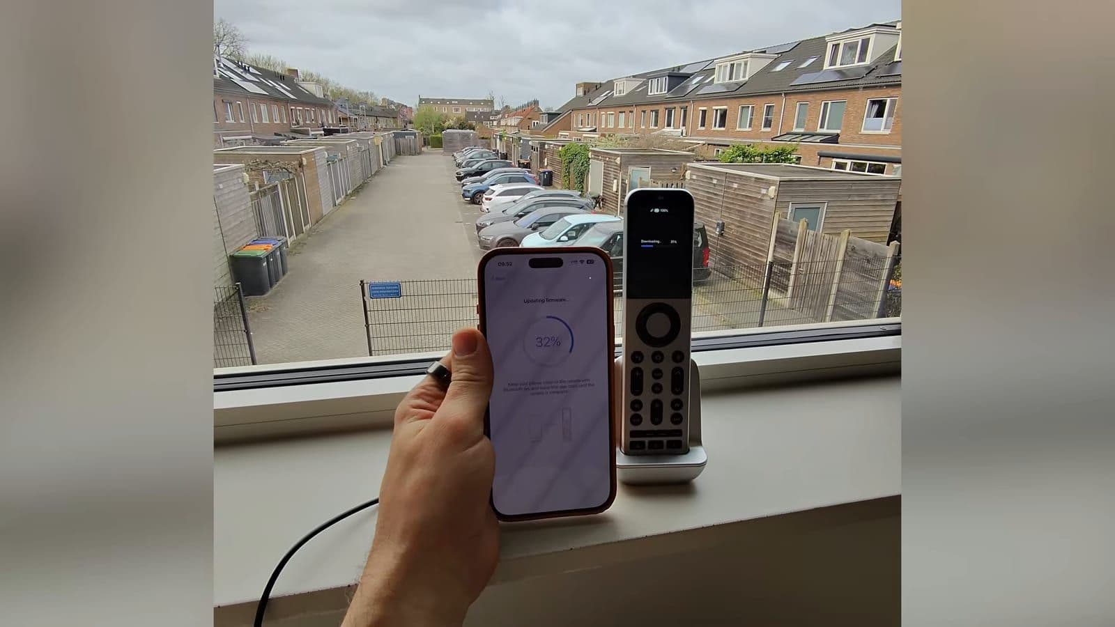 The SofaBaton X2 seated in its charging dock on a windowsill while syncing to the smartphone app