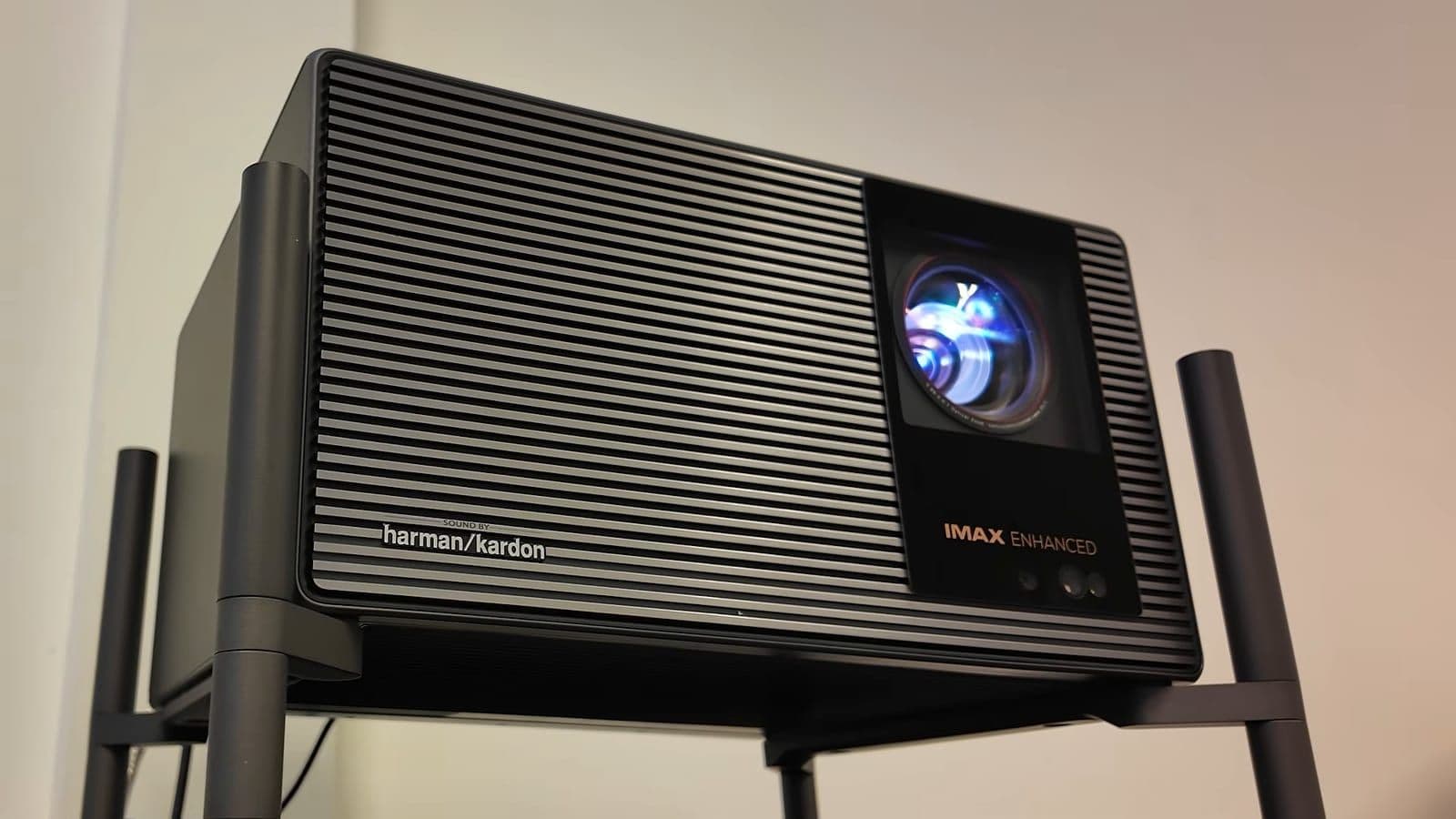 Front angle view highlighting the massive projector lens and Harman Kardon branding