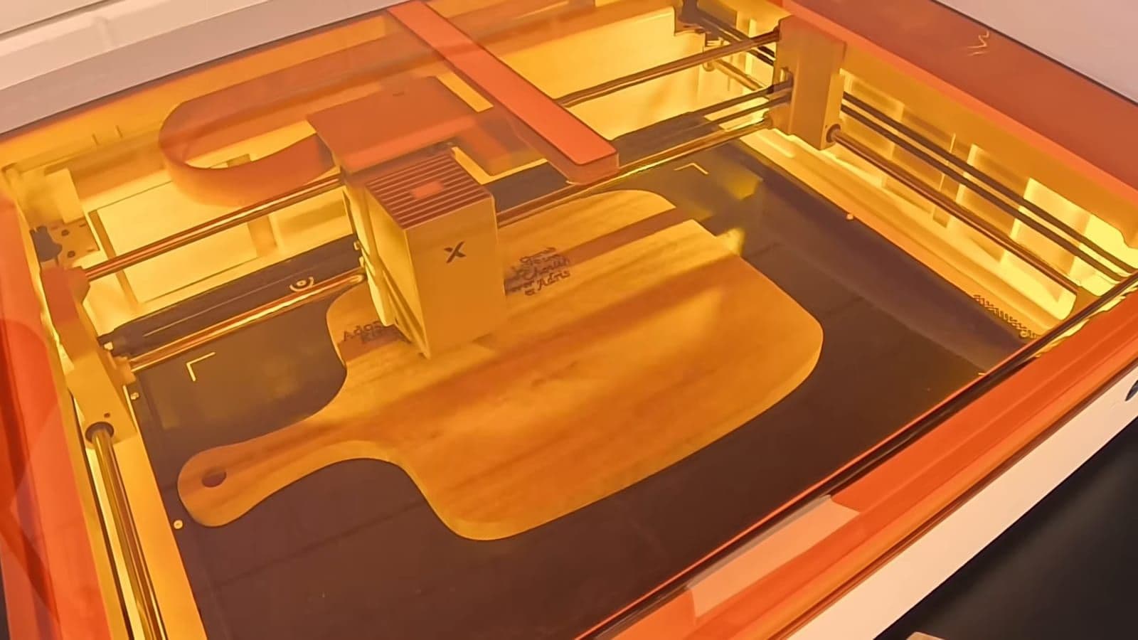 Close-up van de lasermodule die tekst graveert in een houten snijplank